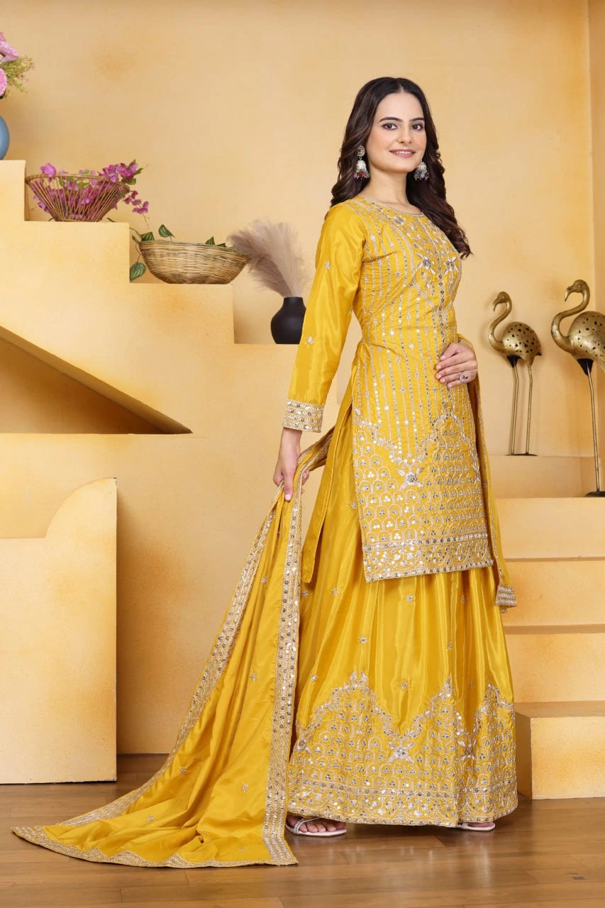 Woman in a yellow traditional outfit standing in a decorative indoor setting.