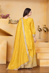 Woman in a yellow traditional outfit standing in a room with decorative elements.