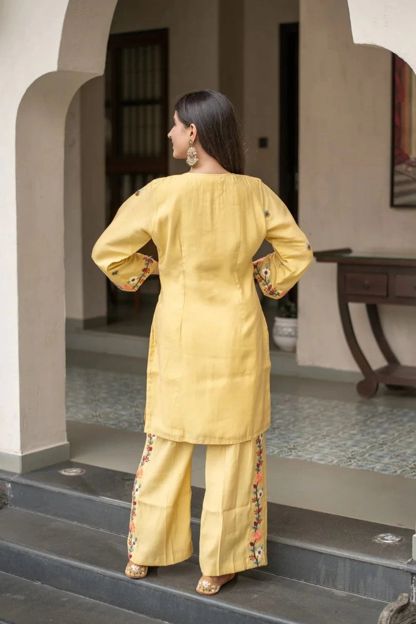 Woman in a yellow traditional outfit standing on steps with a neutral background