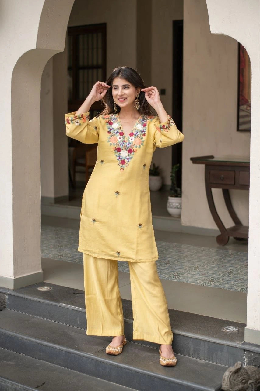 Woman in a yellow traditional outfit standing on steps outside a building.