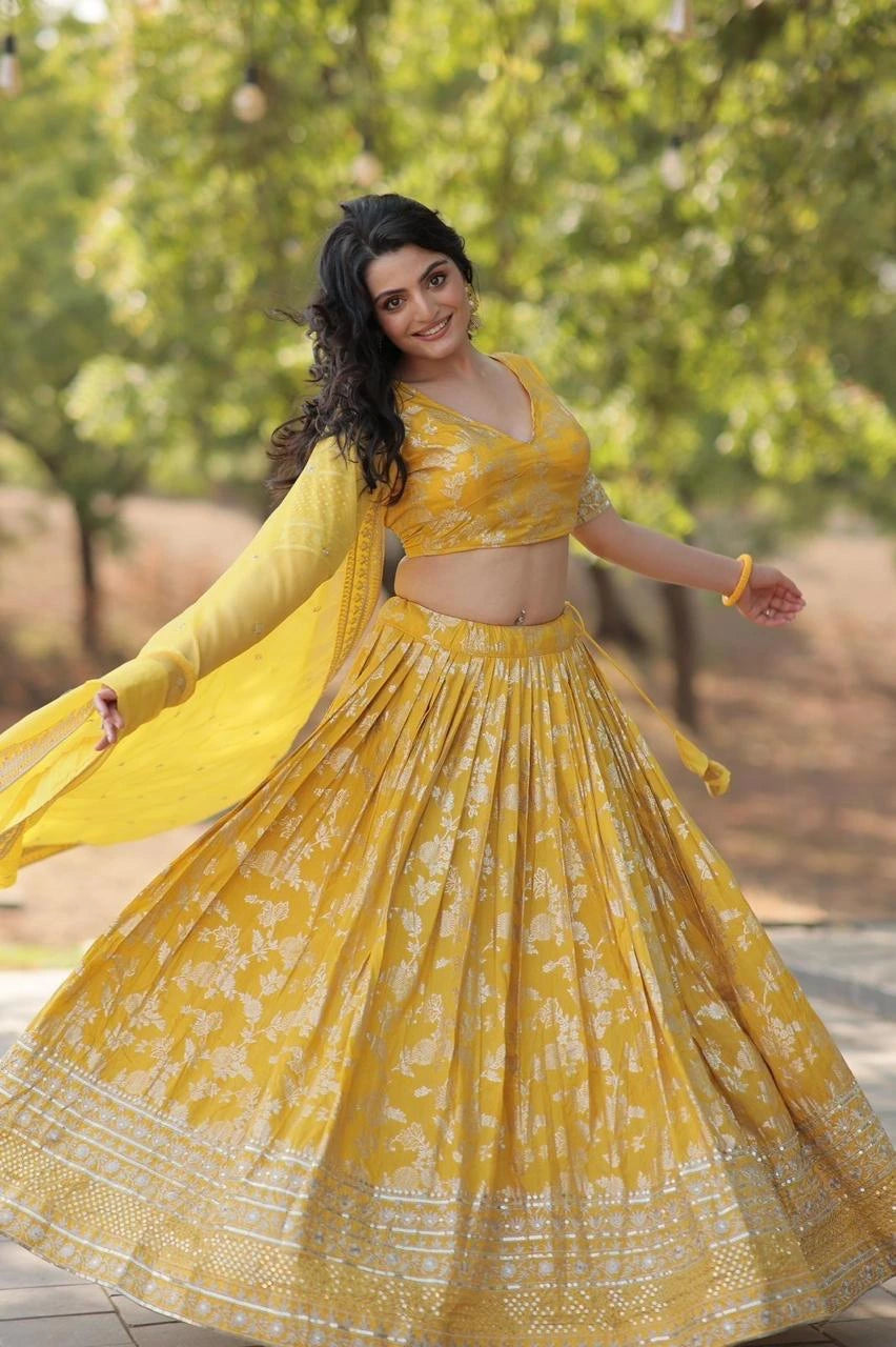 Woman in a yellow traditional outfit with a floral pattern outdoors.