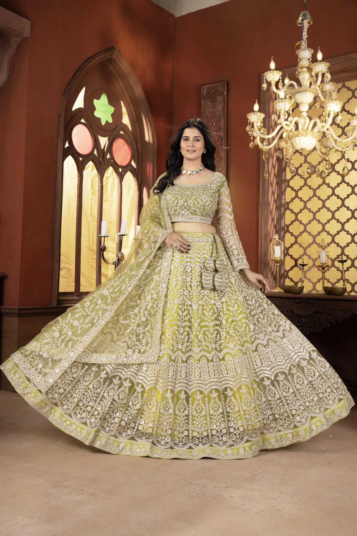 Woman in a traditional embroidered outfit standing in a room with decorative walls and a chandelier.