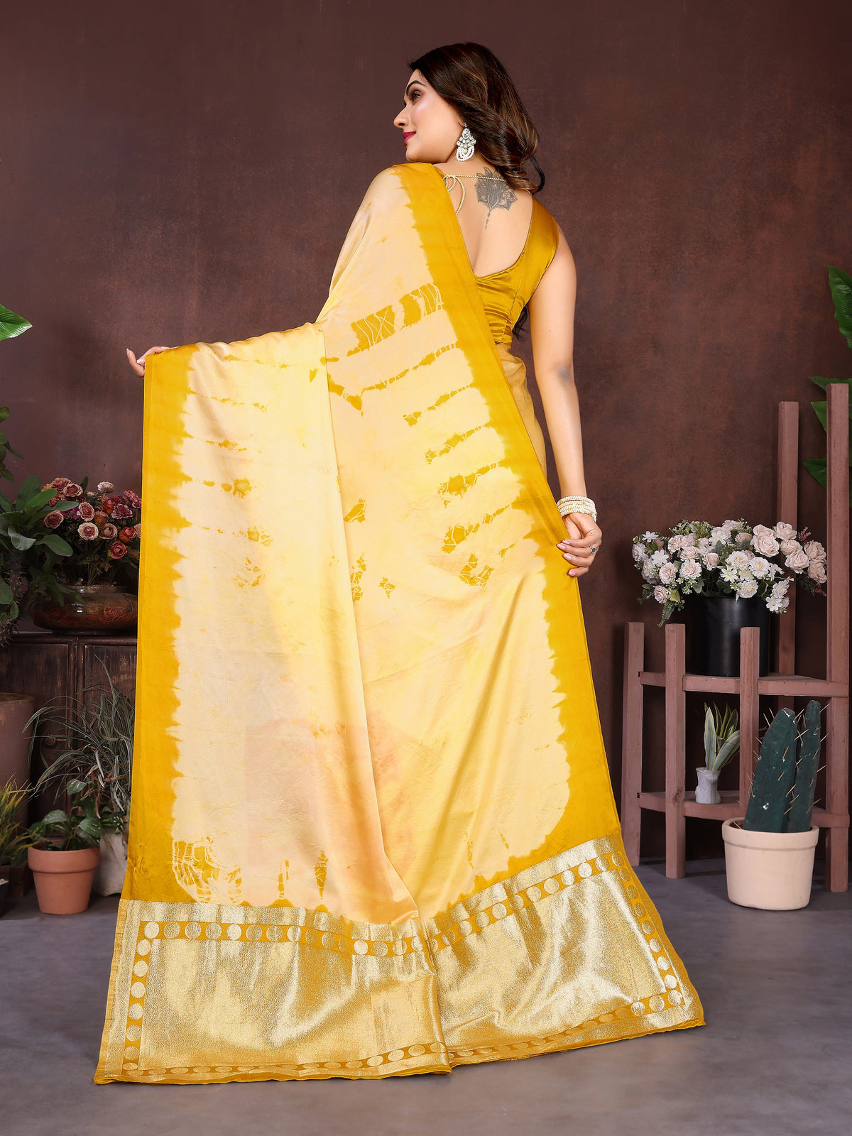 Woman holding a traditional saree with a white and blue pattern in a decorated room.