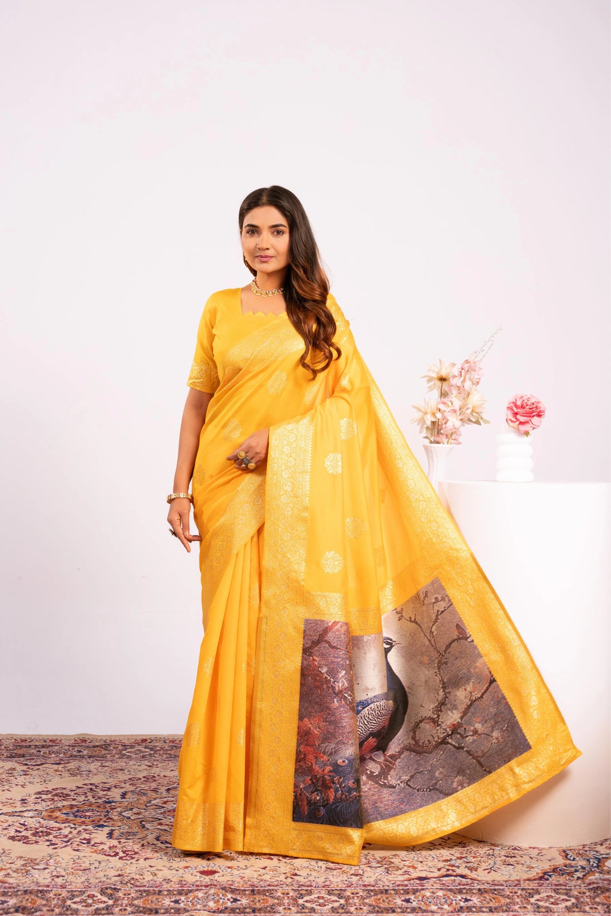 Woman wearing a yellow saree with a patterned border on a white background
