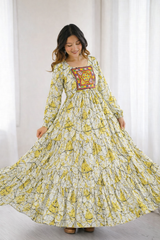 Woman wearing a long, floral dress with a colorful patch on a white background