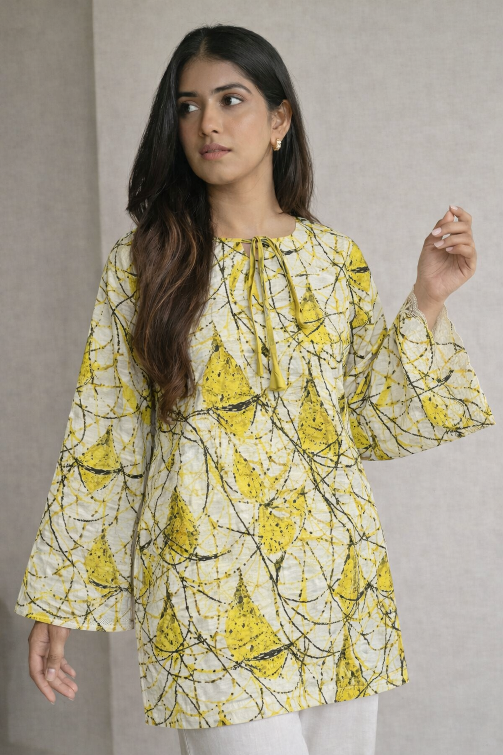 Woman wearing a yellow and black patterned dress against a plain background