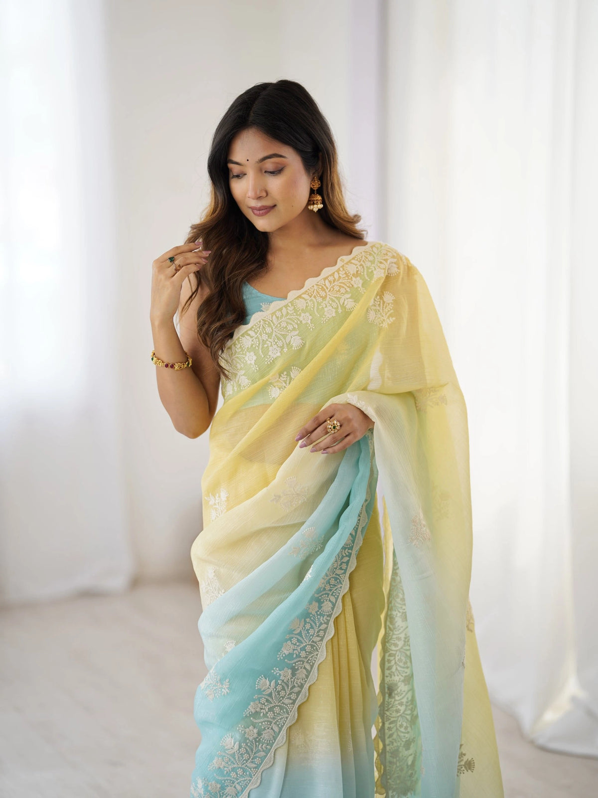 Woman wearing a yellow and blue saree with a white background