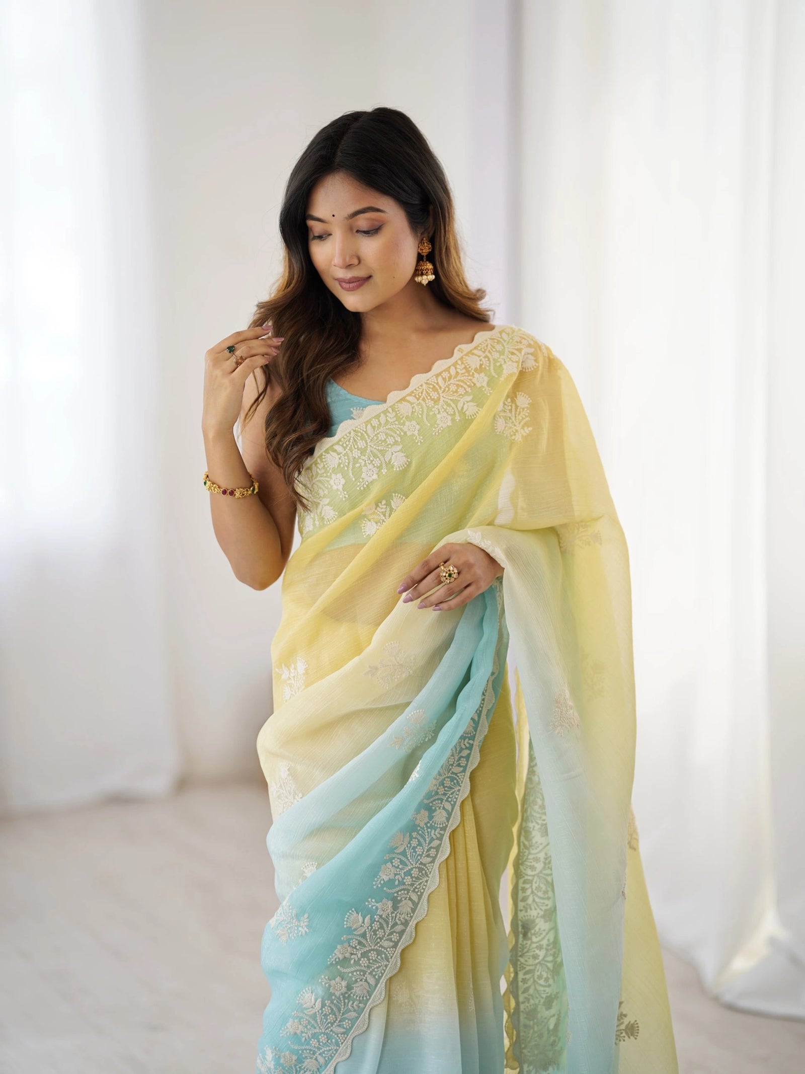 Woman wearing a yellow and blue saree with a white background