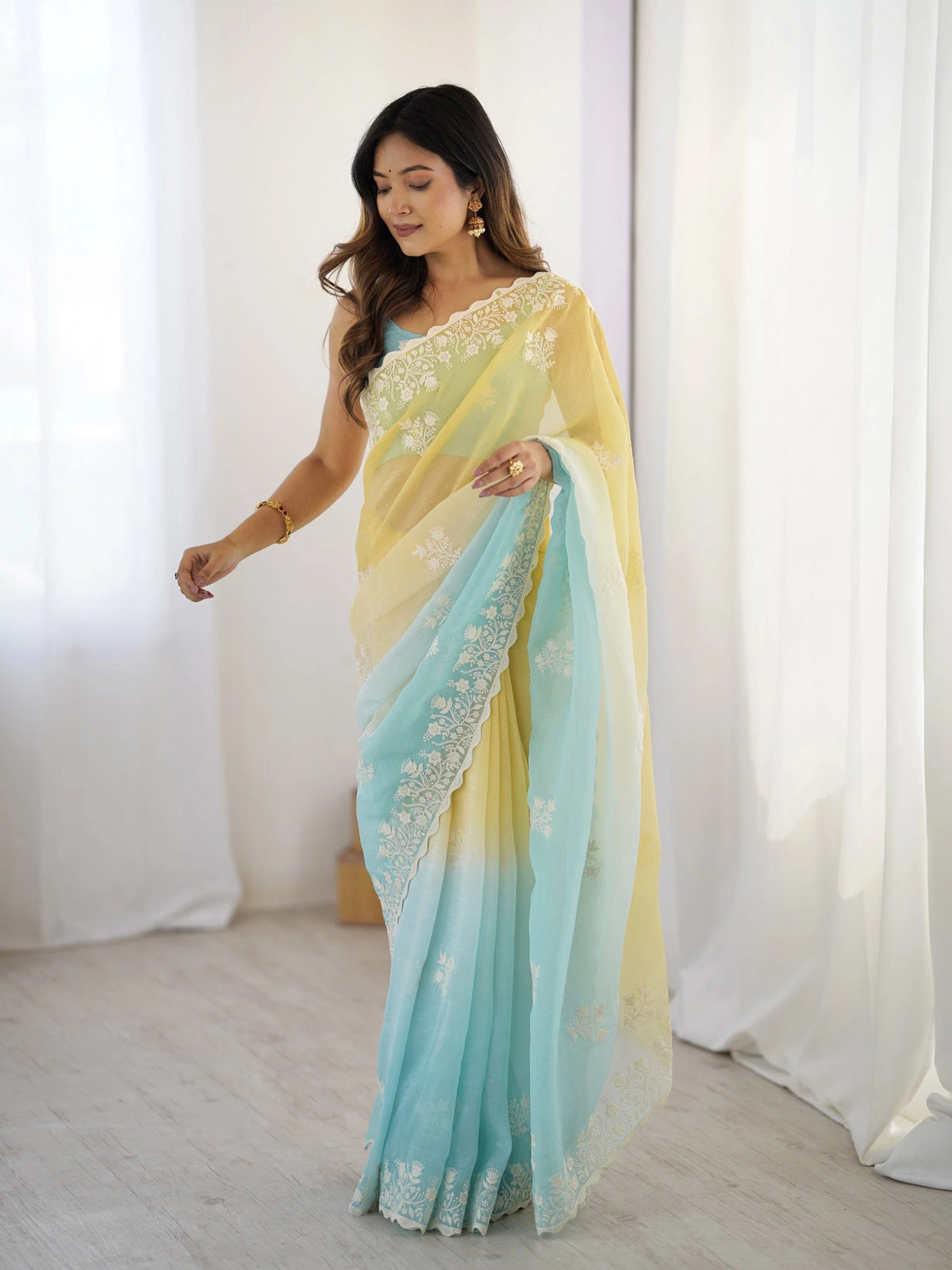 Woman wearing a light blue and yellow saree with a white background