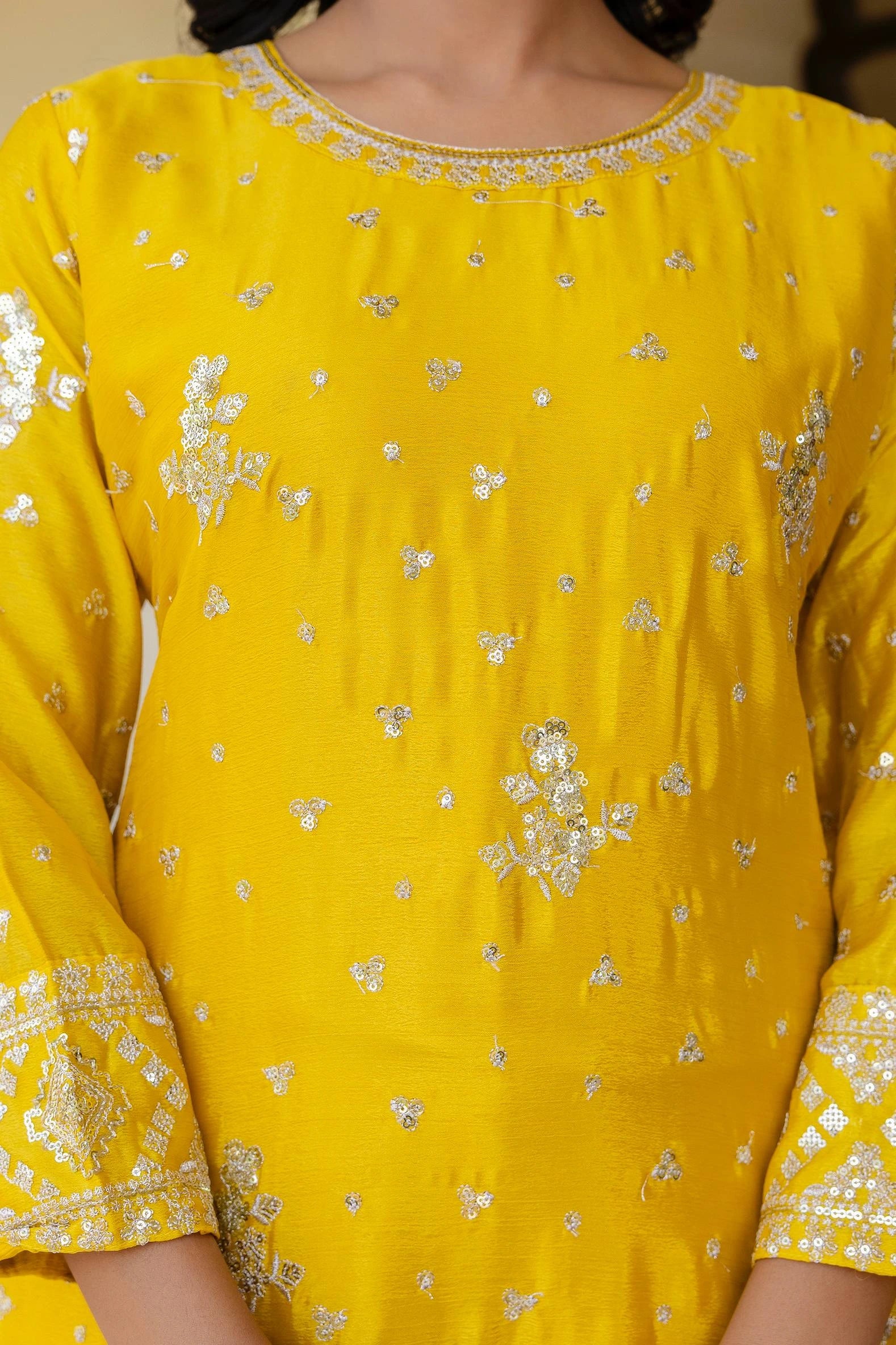 Yellow dress with intricate white patterns on a person wearing it.