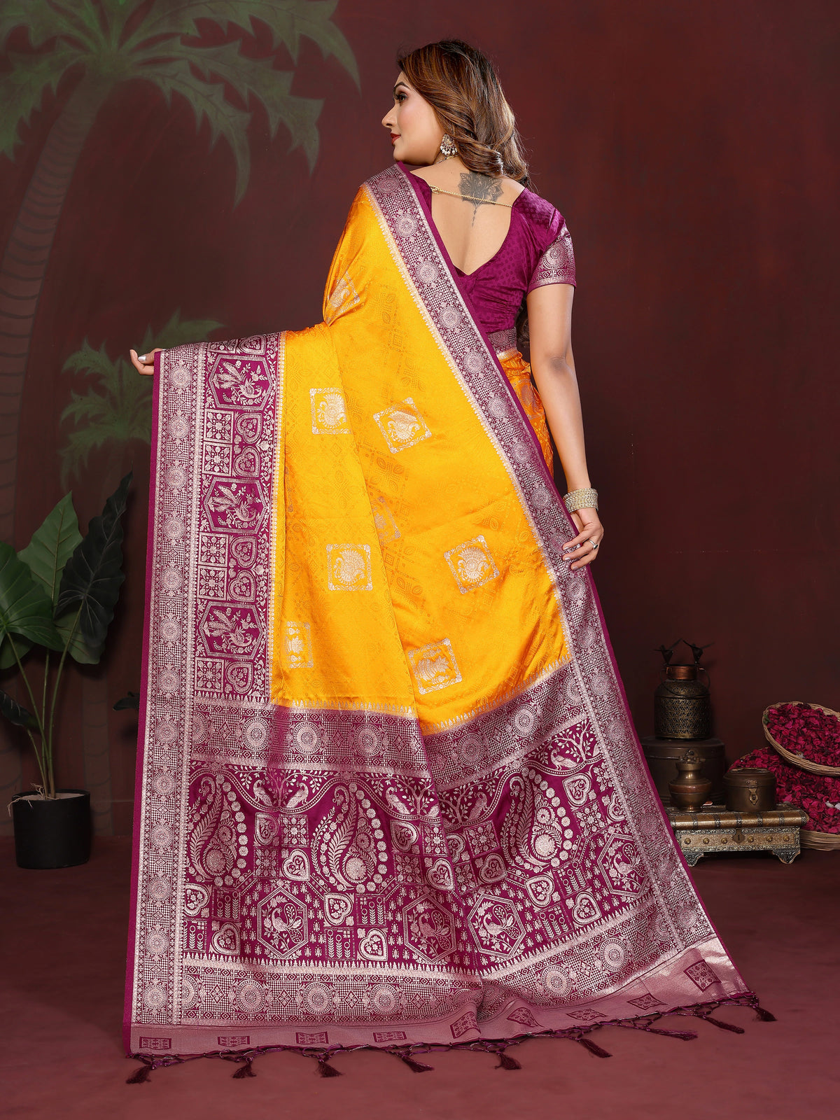 Woman wearing a yellow and purple saree with a patterned border against a dark background