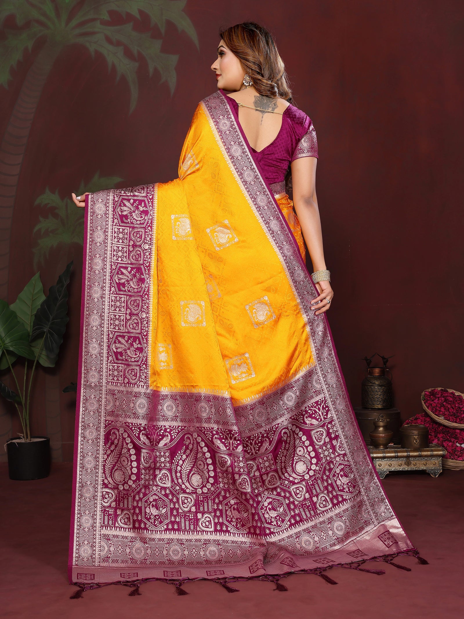 Woman wearing a yellow and purple saree with a patterned border against a dark background