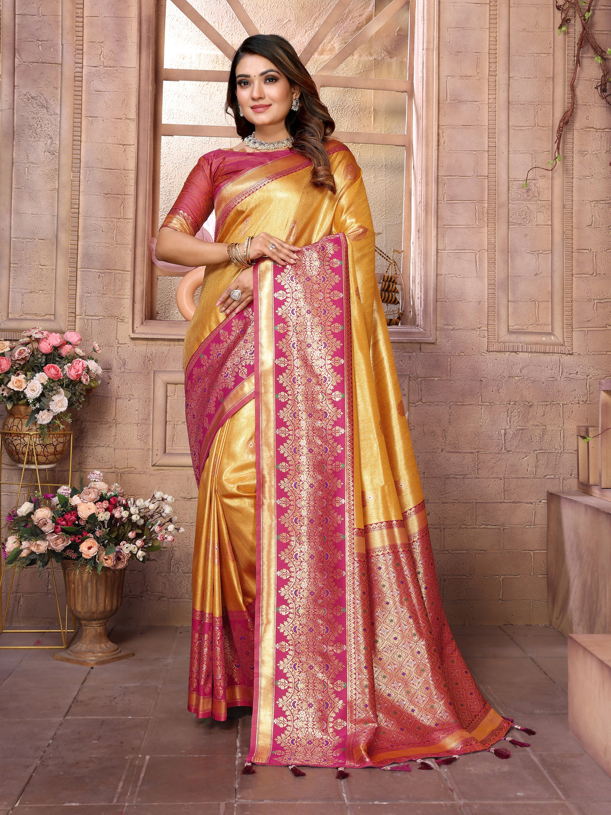 Woman wearing a yellow and pink saree with floral decorations in the background