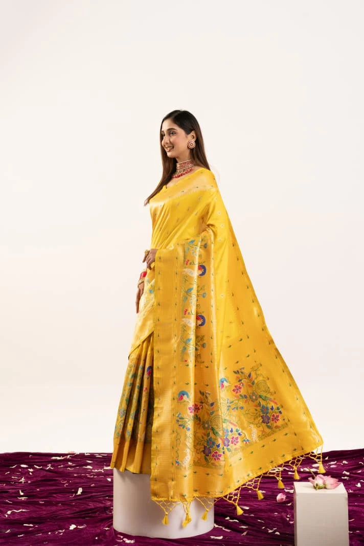 Woman wearing a yellow saree with floral patterns on a white background