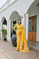 Woman in a yellow saree standing in front of a white building with arches.
