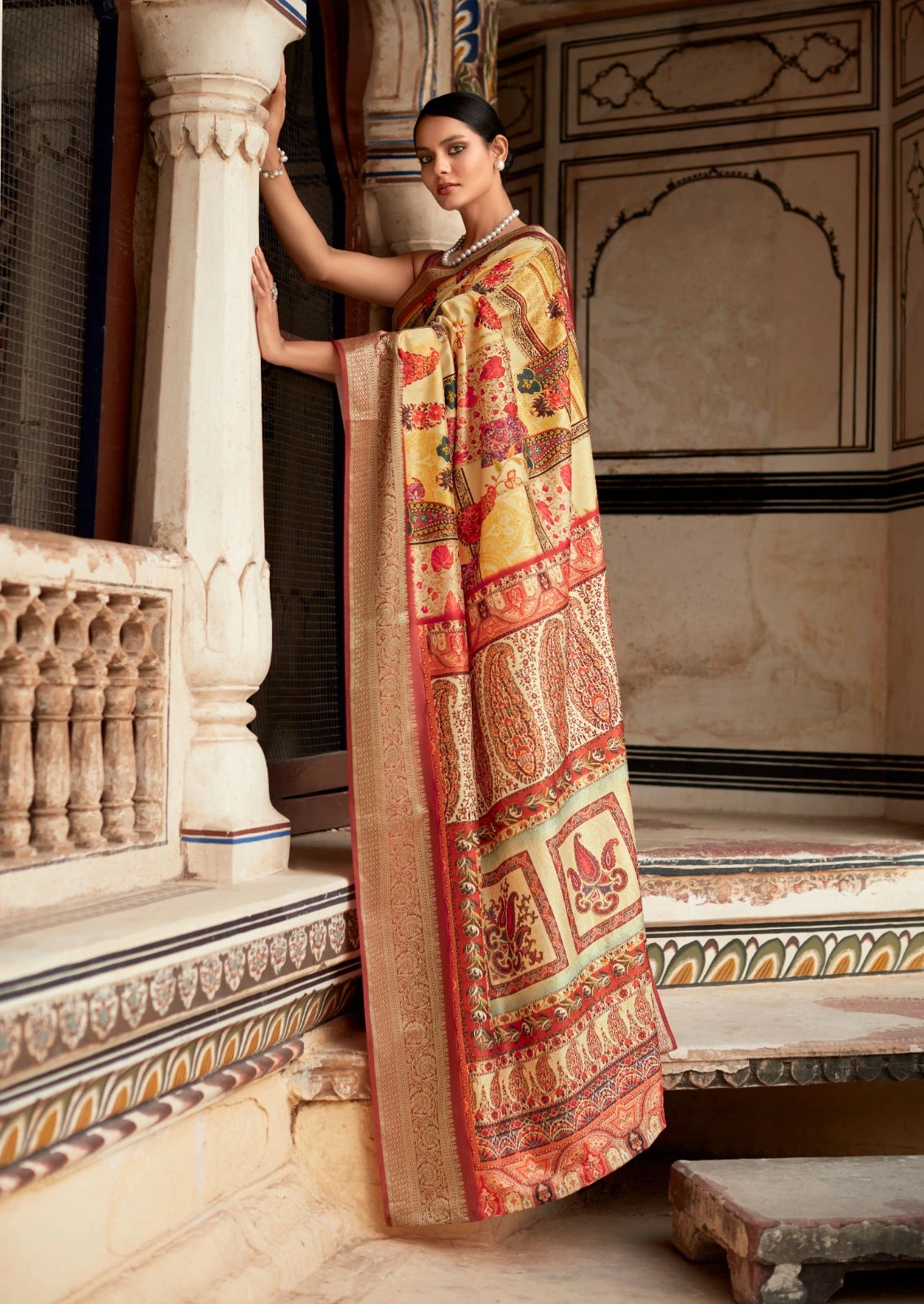 Woman in a traditional saree standing in an ornate indoor setting