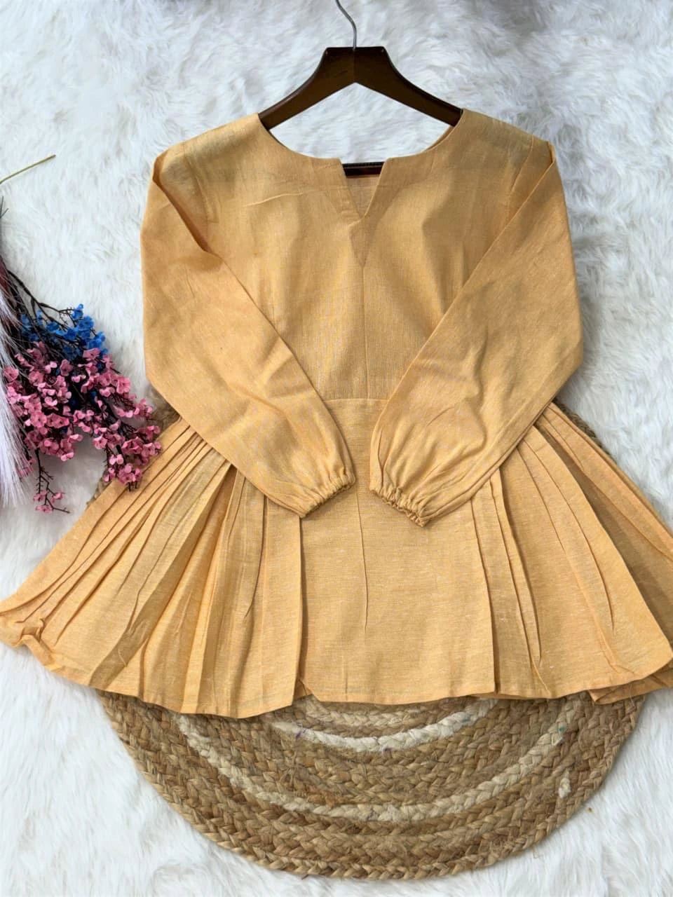 Mustard yellow dress on a hanger with decorative elements on a textured surface
