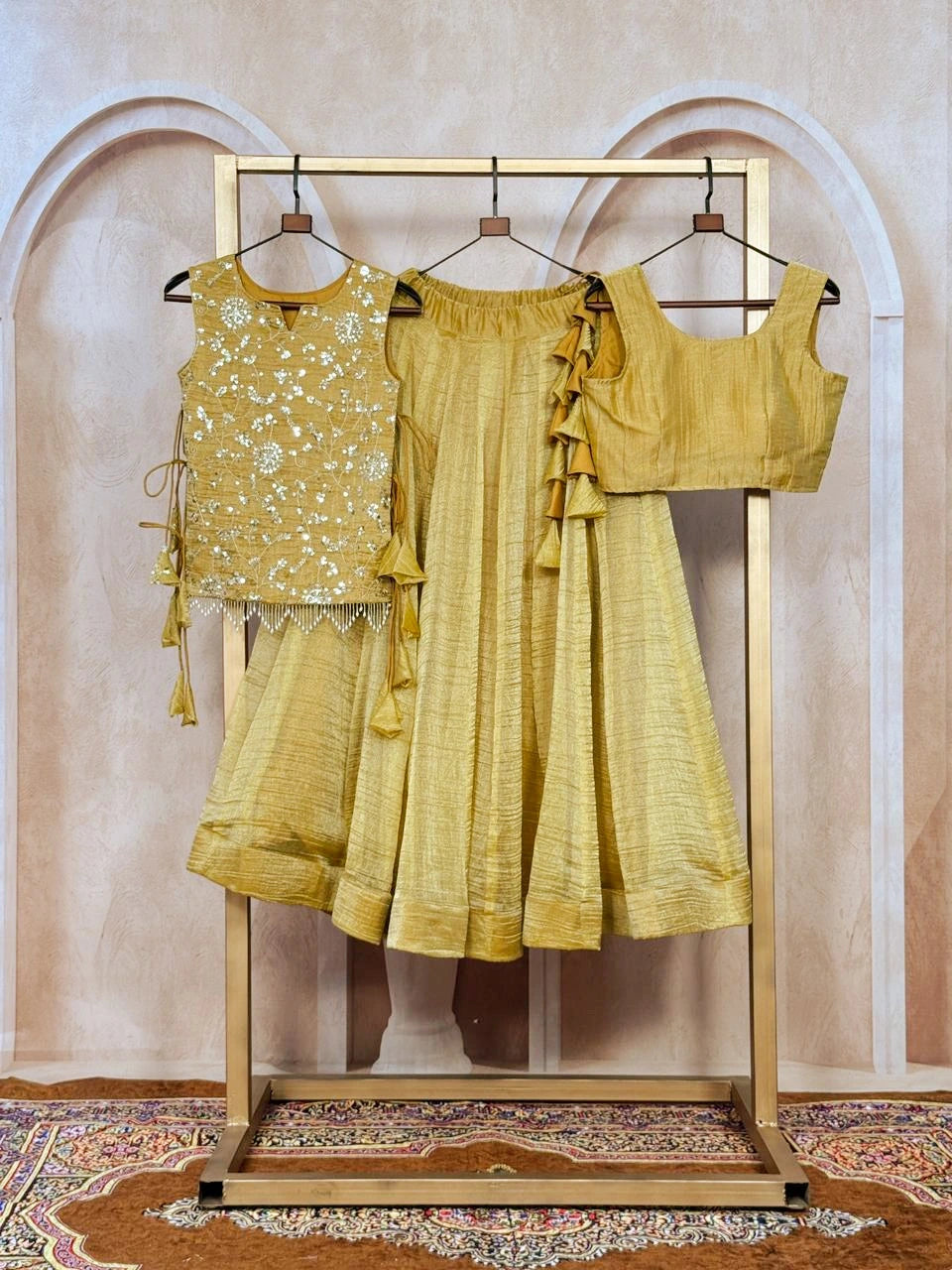 Yellow traditional outfit on a wooden rack against a beige wall.