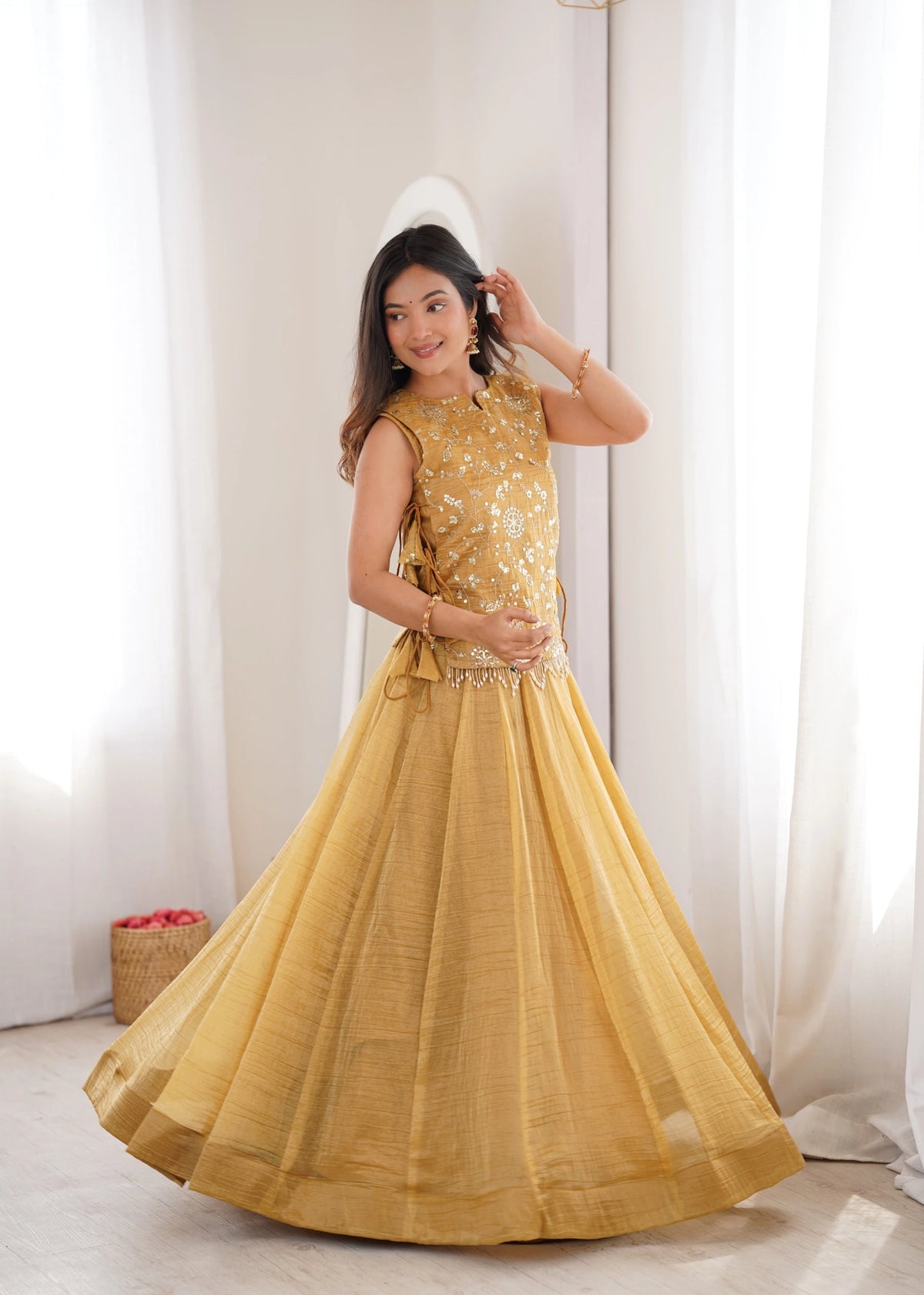 Woman wearing a yellow traditional outfit with a white curtain background