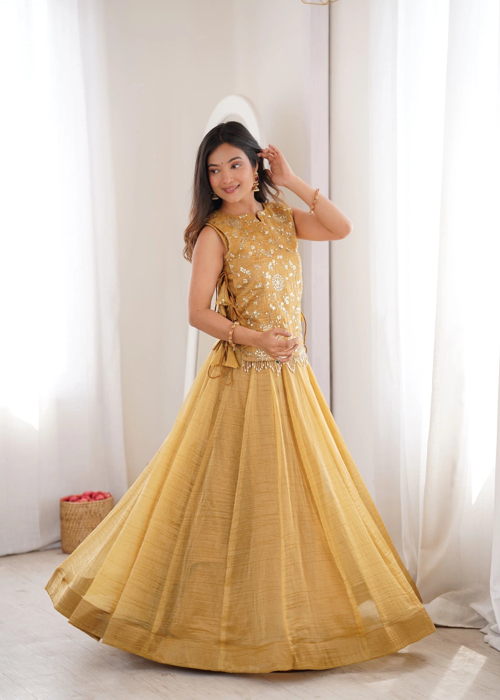Woman wearing a yellow traditional outfit with a white curtain background