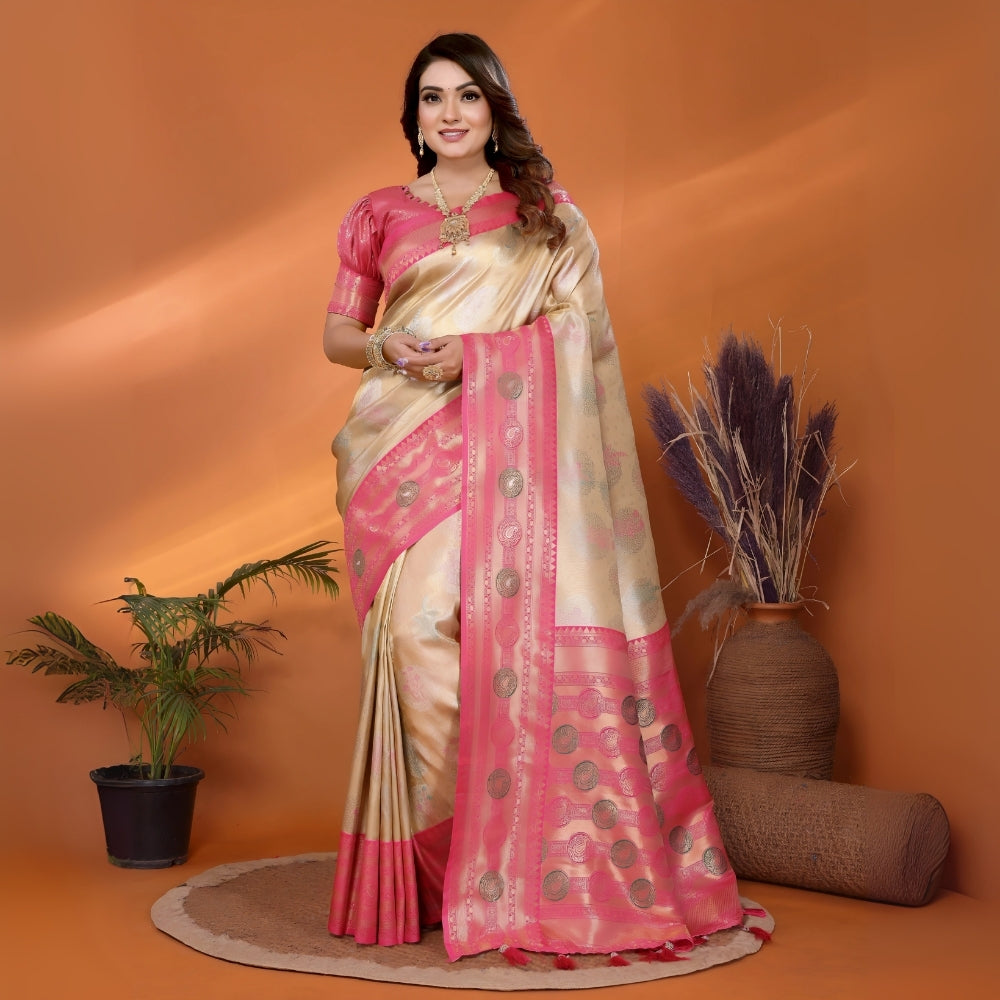 Woman wearing a pink and beige saree with a plant and vase in the background
