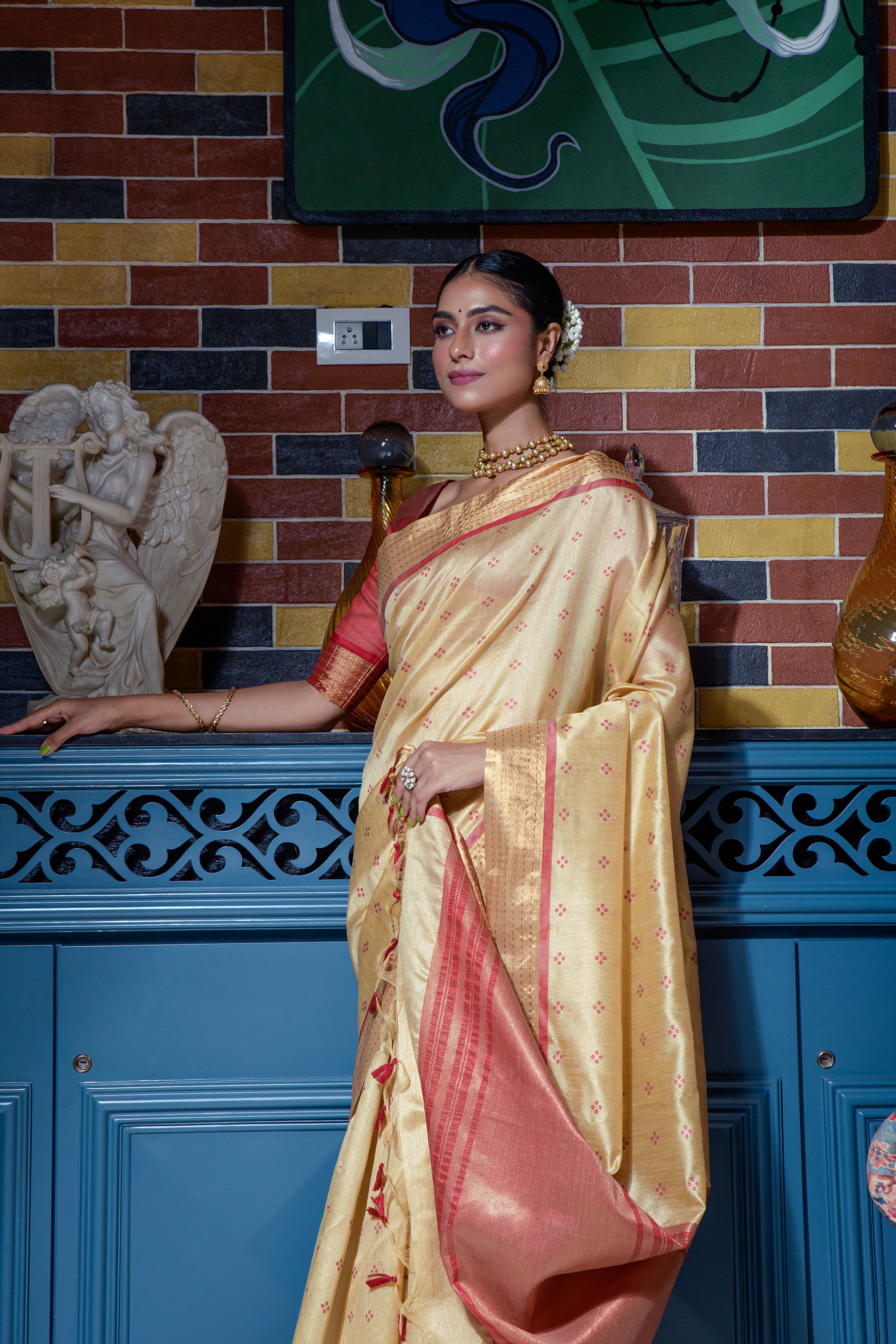 Close up of beige saree with zari work and red border
