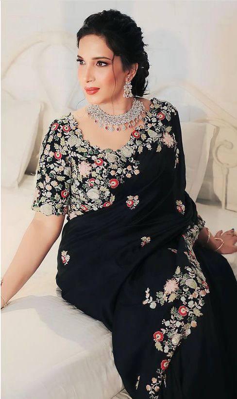 Black saree with intricate embroidery work featuring floral patterns in vibrant colors, draped elegantly over a mannequin