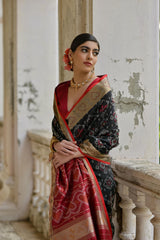Woman draped in elegant black Pochampali Ikkat saree with zari weaving, styled gracefully on a vintage balcony