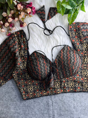 Black and red printed padded blouse with geometric and floral patterns, displayed on a white fur surface with artificial flowers and green leaves in the background.
