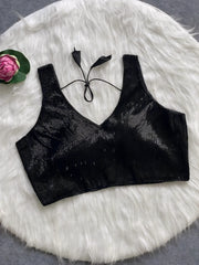  Black sequin sleeveless blouse with tie-back detail, displayed on a white fur background with a pink floral prop in the corner.