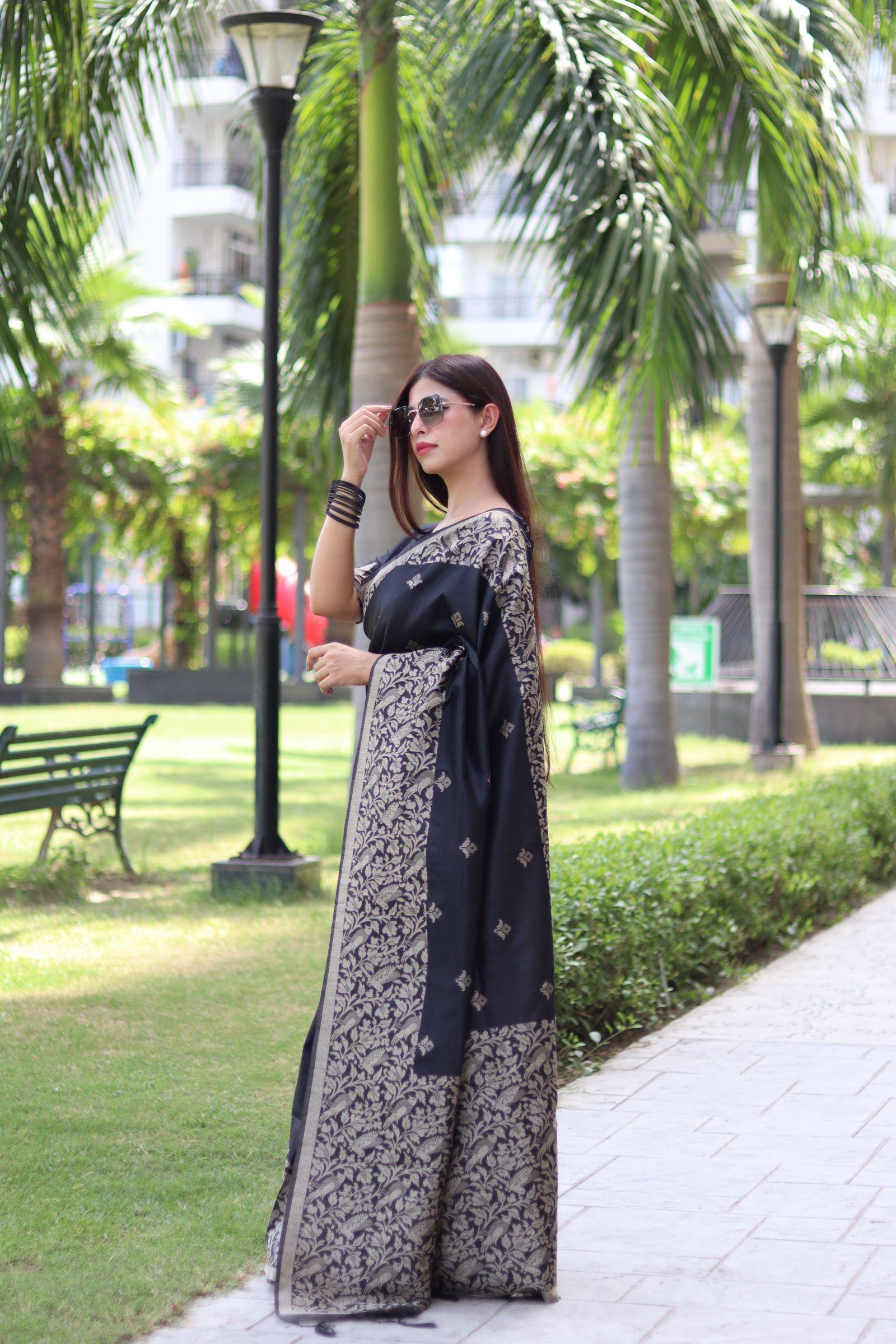 Woman wearing black traditional weaving saree posing gracefully in ethnic attire outdoors