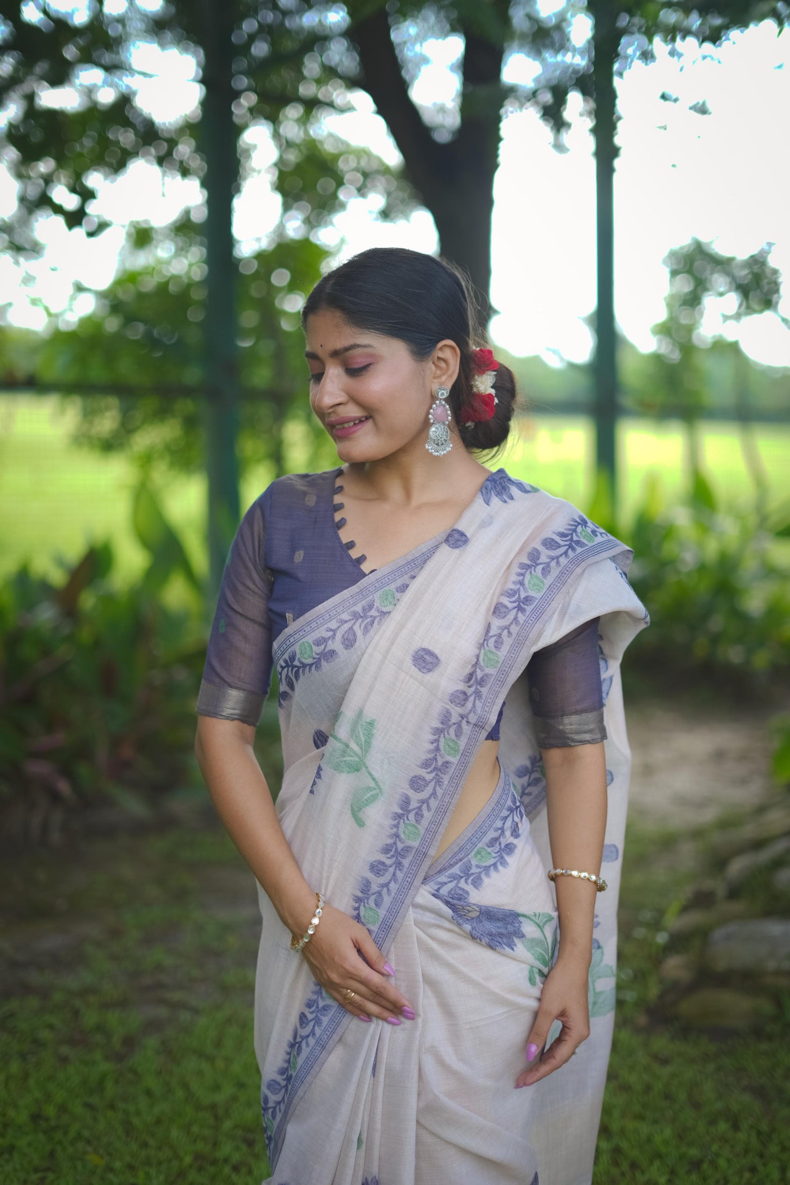 Close-up of woman in blue resham weaving saree with floral design and elegant traditional styling in natural background