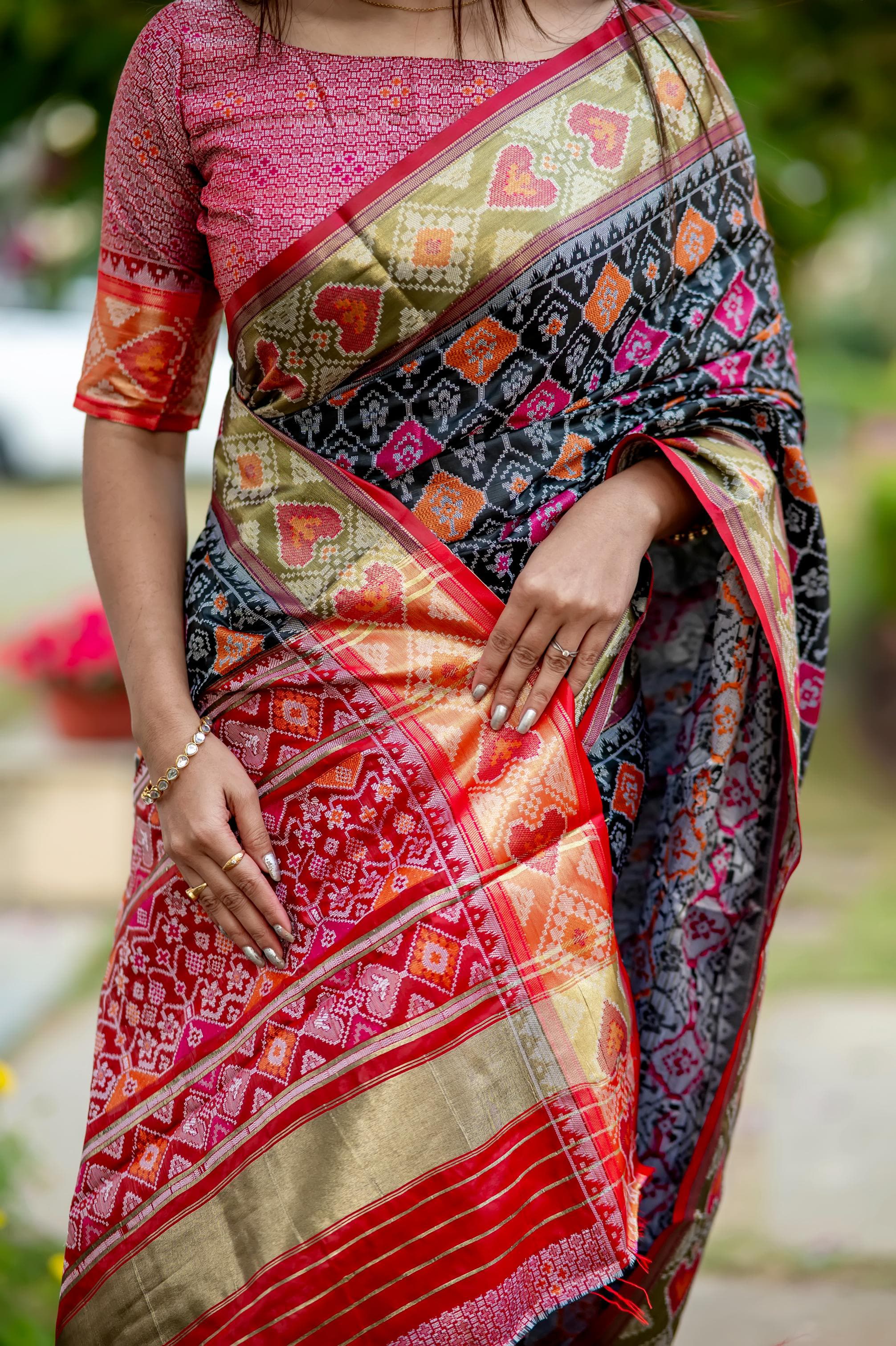 Woman wearing a blue saree with intricate zari work, standing gracefully in an outdoor setting
