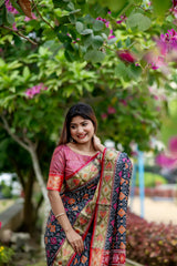 Woman wearing a blue saree with intricate zari work and a golden border, standing in an outdoor setting