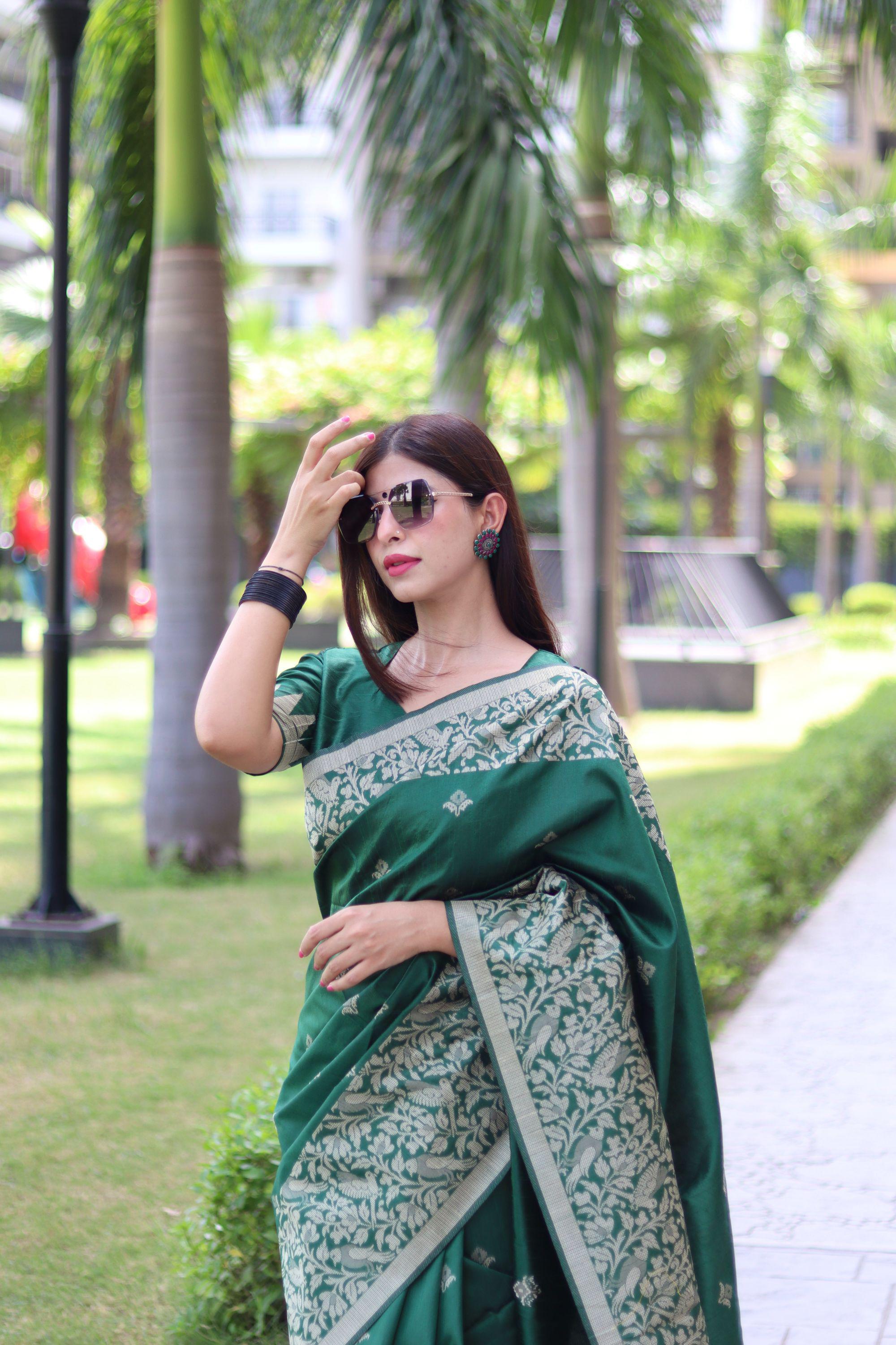  Woman in deep green traditional weaving saree standing elegantly in a garden with palm trees