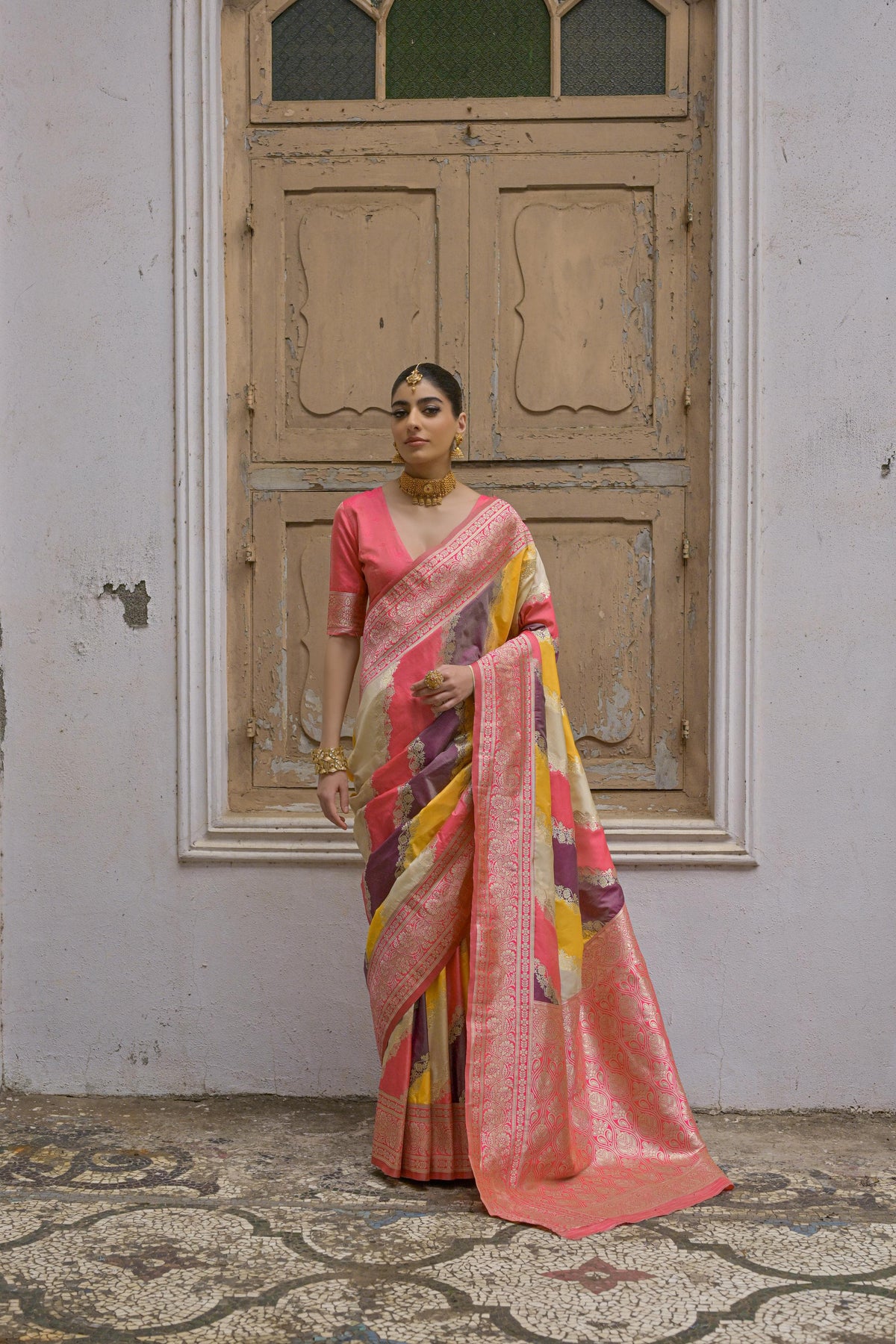 A woman wearing a tulip pink floral printed saree, standing outdoors in elegant traditional Indian ethni