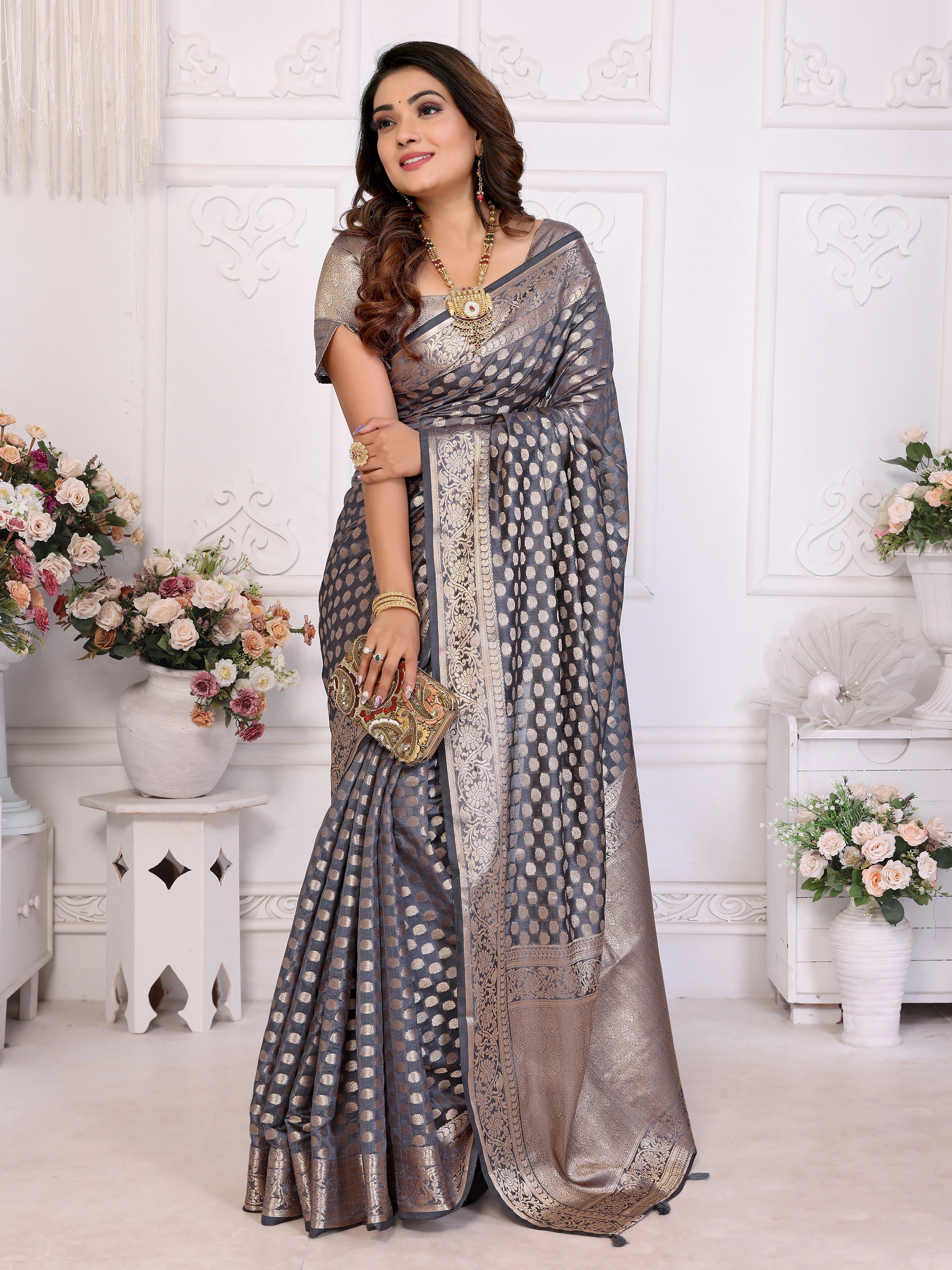 Woman wearing a gray saree with a white background and decorative elements.