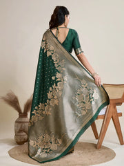 A woman models a luxurious Dark Green Soft Kanjivaram Silk Saree. The saree features striking large floral and scattered motifs woven in metallic antique gold Zari on the body and wide pallu. She wears a matching long-sleeve green blouse and accessorizes with a heavy gold Kundan choker necklace and earrings.