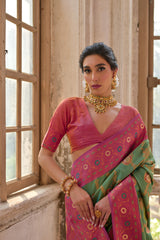 A woman models a striking Moss Green Banarasi Silk Saree with gold Zari weaving. The saree has a wide, ornate Fuchsia Pink border and pallu featuring traditional geometric Zari weaving. She wears a pink and gold blouse and heavy gold Kundan jewelry.