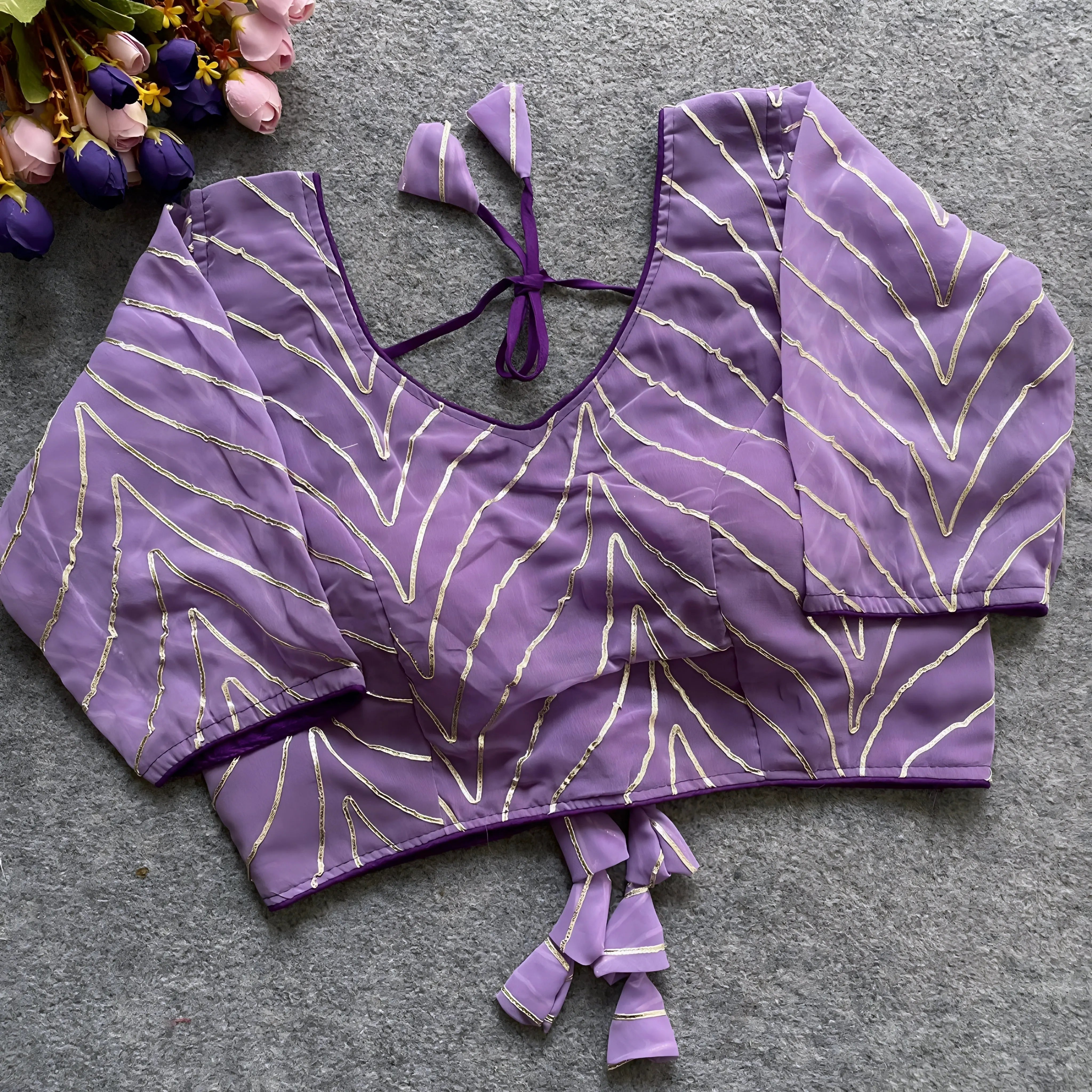 Lavender designer blouse featuring golden thread embroidery, deep back design, and matching fabric tassel tie-up