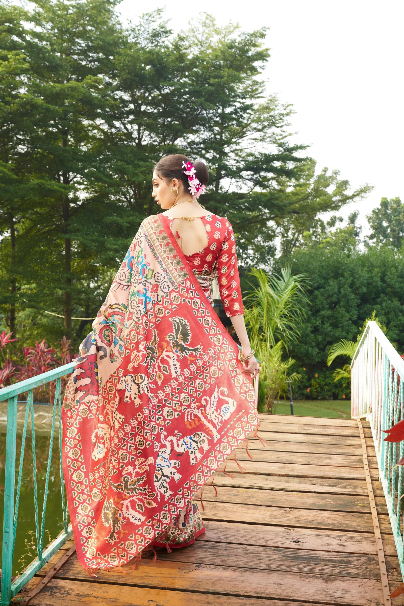 Light beige saree with Patola print seen from behind on a bridge outdoors