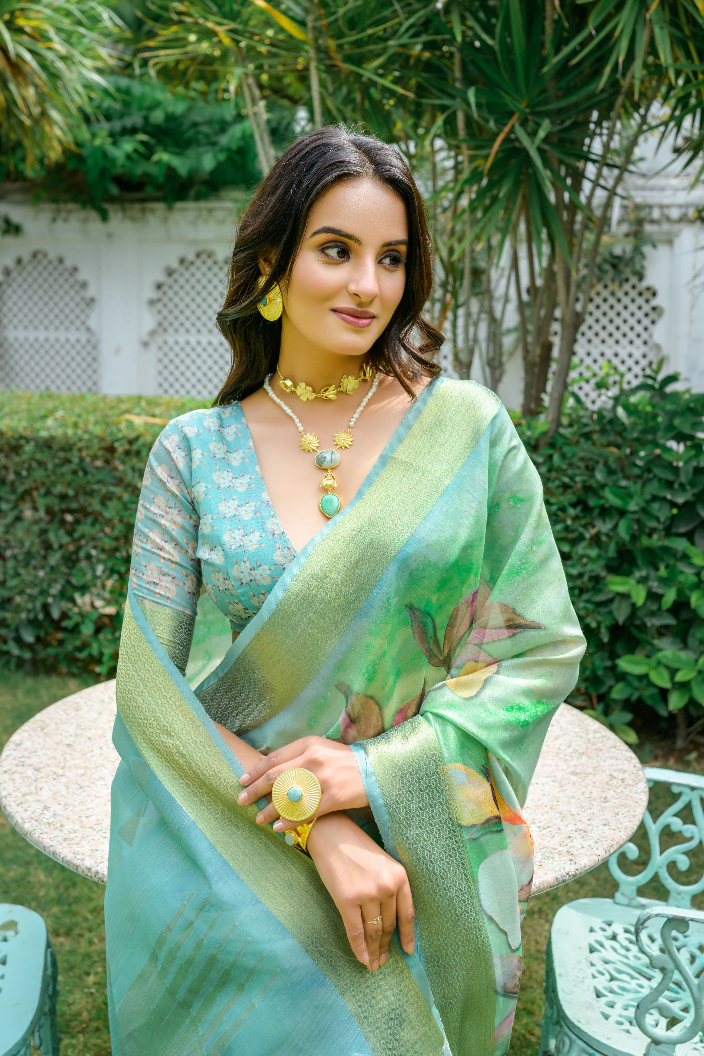 Woman wearing light green pastel saree with zari work and floral design 