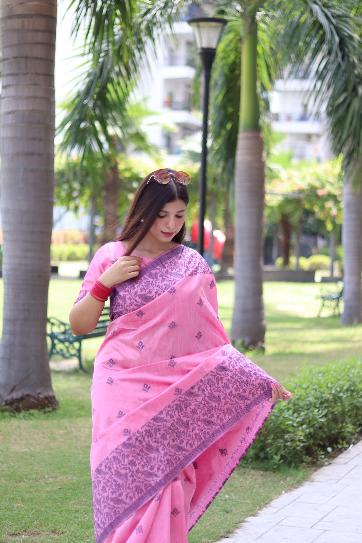 Woman in light pink traditional weaving saree showcasing elegant ethnic style in garden background