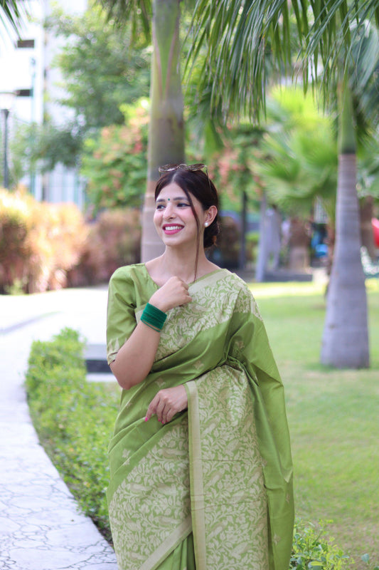 Woman wearing light pista traditional weaving saree posing gracefully in an outdoor garden setting