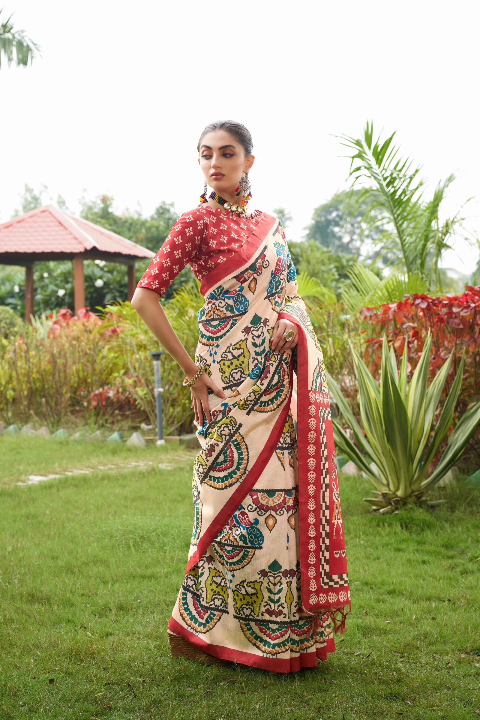 Light beige saree with Patola print and red border outdoors