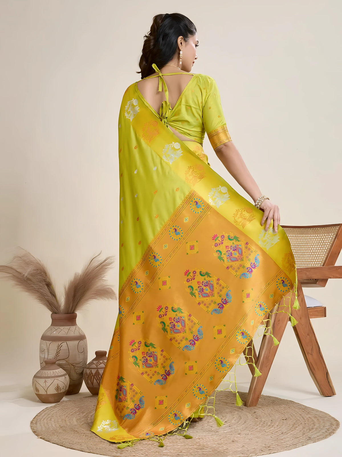 A woman models a luxurious Lime Green Soft Silk Saree. The saree features scattered metallic motifs and a wide pallu in contrasting yellow/gold, richly woven with multi-colored peacock and floral designs. She wears a matching lime green blouse and heavy gold Kundan jewelry, posing indoors.