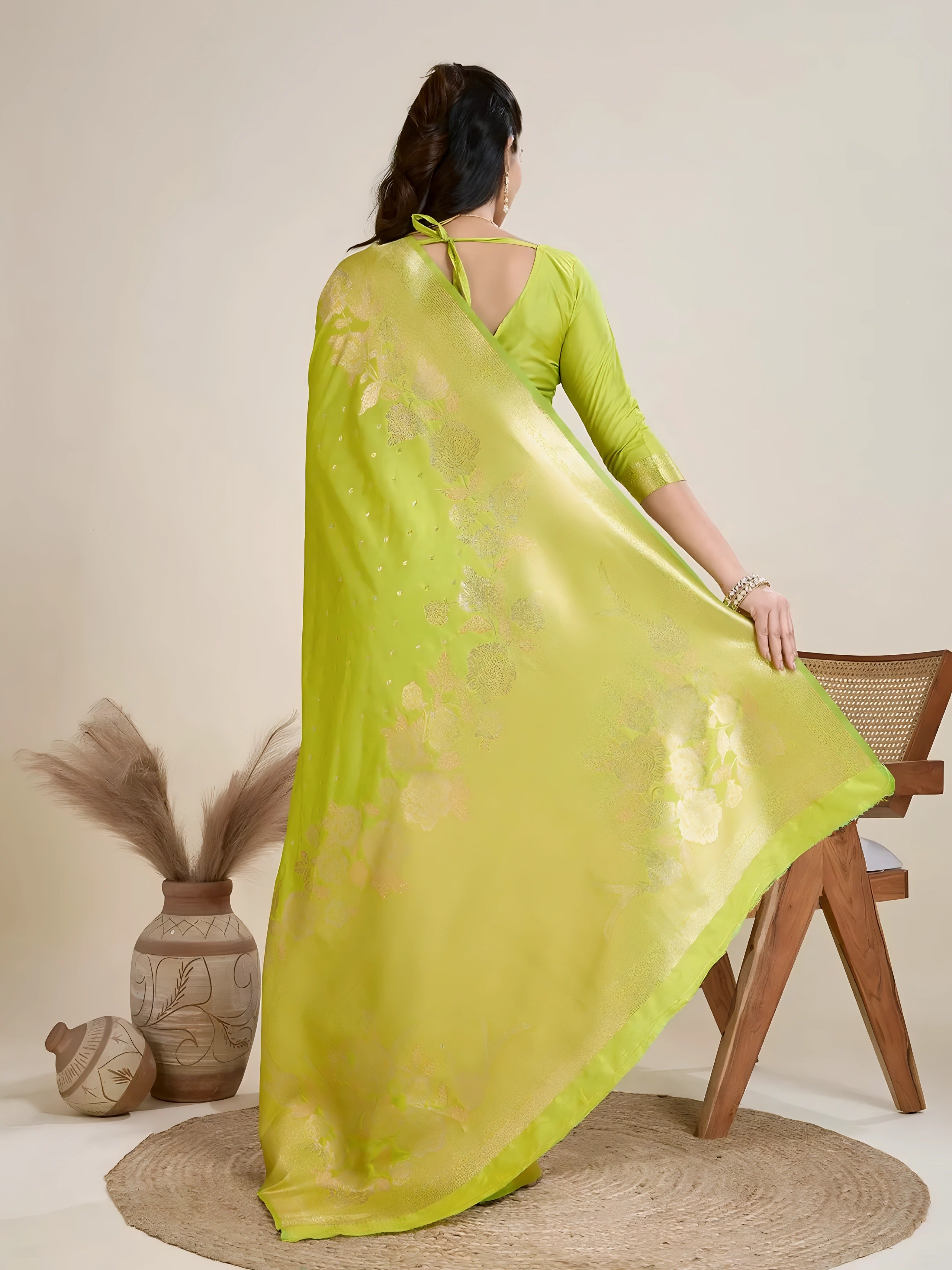 A woman models a luxurious Lime Green Soft Kanjivaram Silk Saree. The saree features striking large floral and scattered motifs woven in tone-on-tone green and gold Zari on the body and wide pallu. She wears a matching three-quarter sleeve green blouse and accessorizes with a heavy gold Kundan choker necklace and earrings.