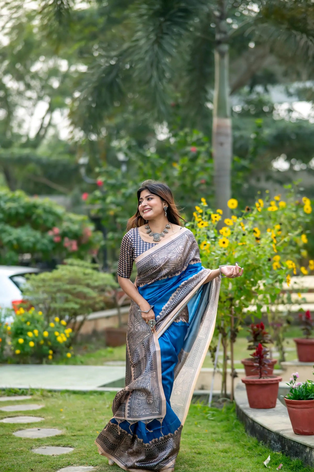 Woman wearing blue Madhubani print saree posing outdoors in traditional Indian ethnic outfit