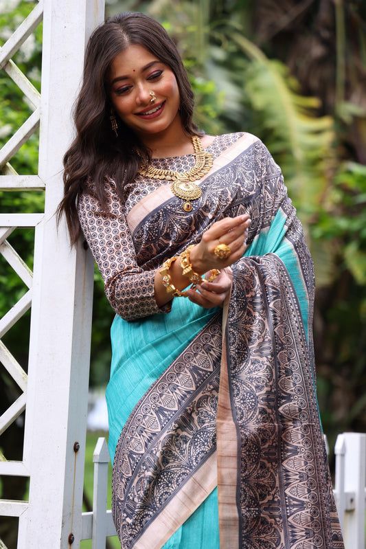 Woman wearing traditional powder blue Madhubani print saree with intricate designs and ethnic jewelry in a green outdoor setting