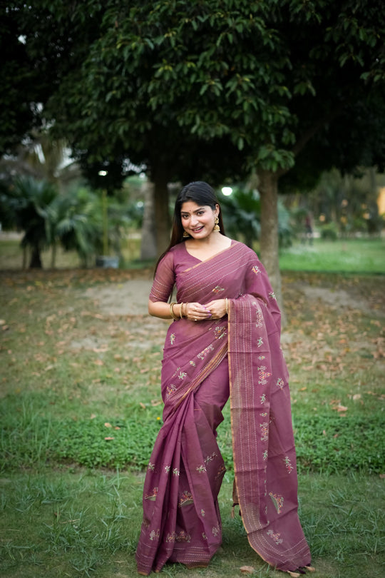 Woman wearing magenta traditional weaving saree with intricate patterns in a garden setting